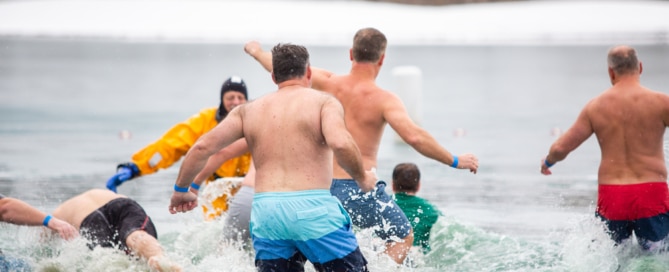 People running towards the ocean on the brach in the winter.