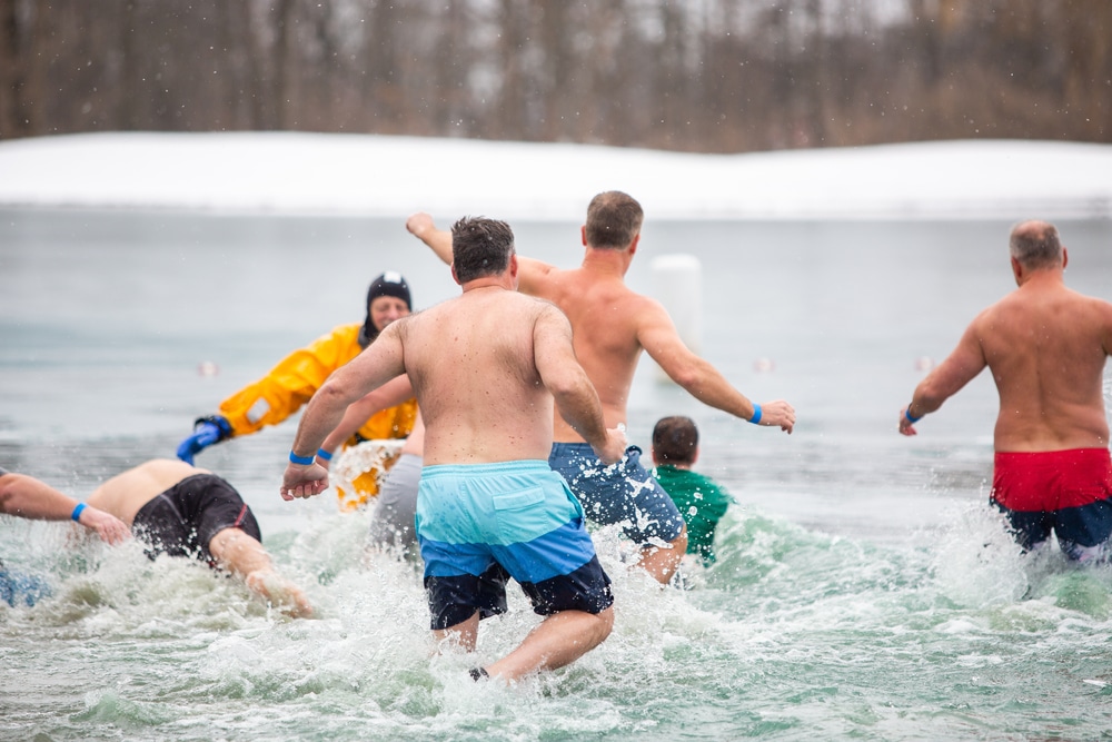 People running towards the ocean on the brach in the winter.